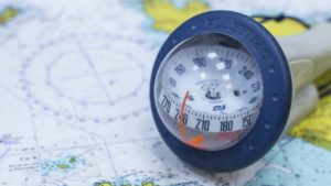 Auf einer Karte liegt ein Kompass (Kugel in dem die Breiten-Grade anhand eines schwebenden Navigators abgemessen werden können)