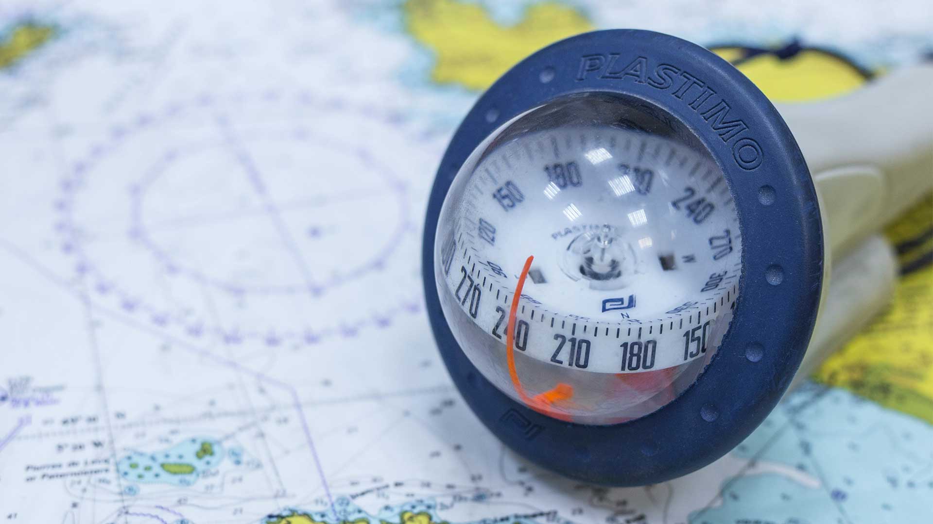 Auf einer Karte liegt ein Kompass (Kugel in dem die Breiten-Grade anhand eines schwebenden Navigators abgemessen werden können)